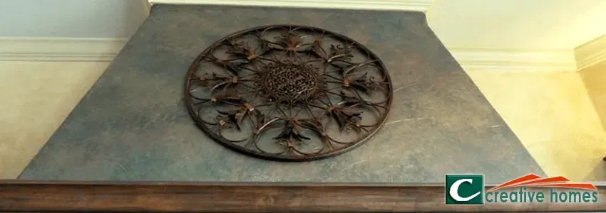 A kitchen range hood with a metallic finish and a decorative circular metal design.