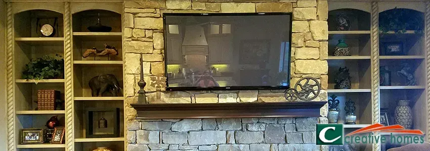 Built-in bookshelves flank a stone fireplace with a mounted television.