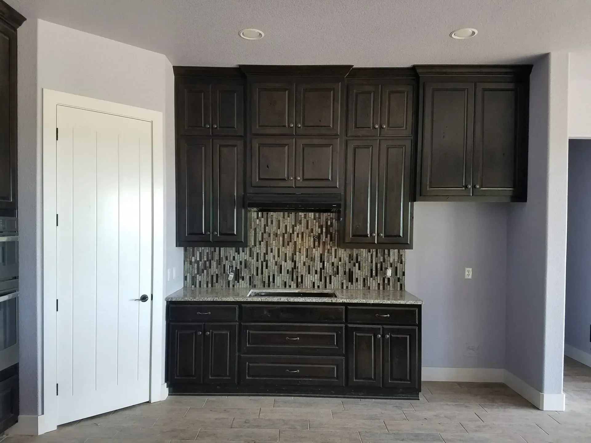 Kitchen with dark brown cabinets, a tiled backsplash, and light gray walls.