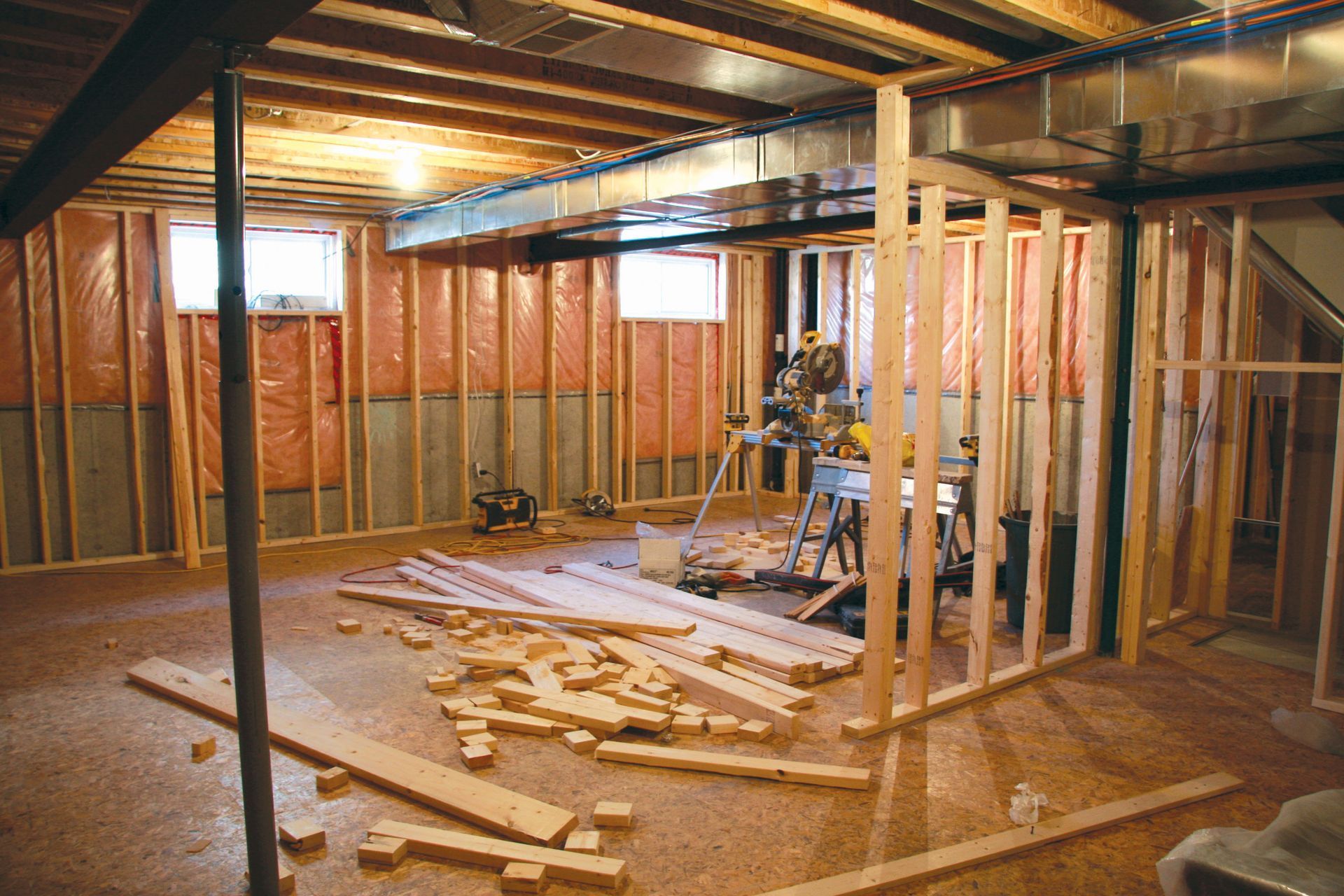 Basement under construction, with wooden framing, insulation, and tools scattered.