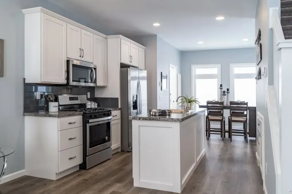 Kitchen with white cabinets, stainless steel appliances, and a gray granite countertop island.