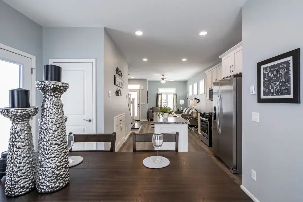 Dining room looking into the kitchen. Dark wood table with large candlesticks. Light gray walls.