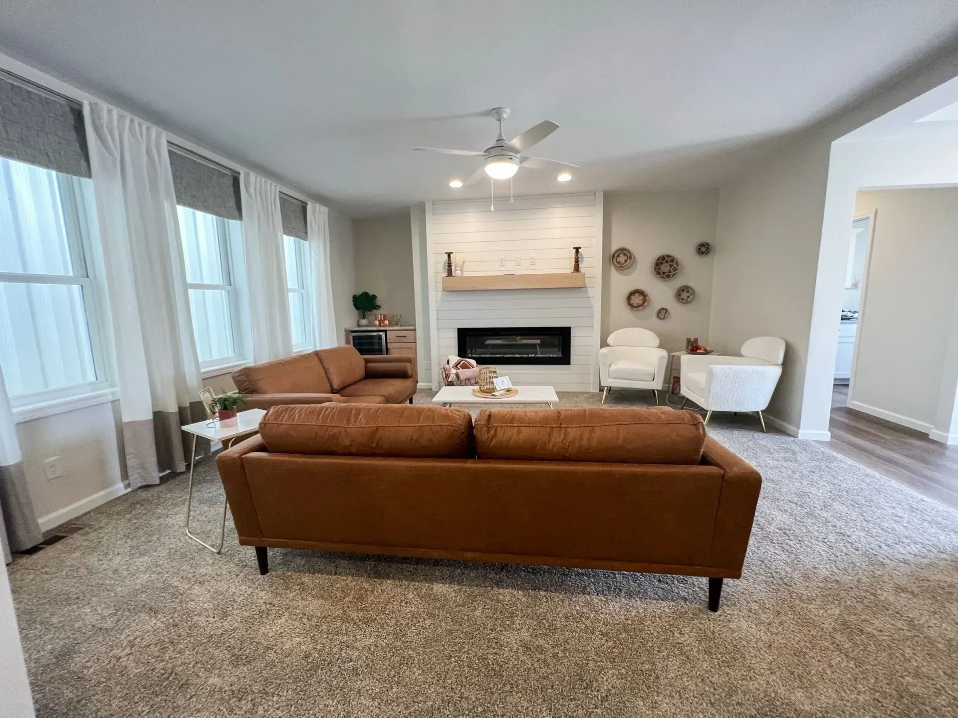 Living room with two brown leather sofas, fireplace, and white chairs.