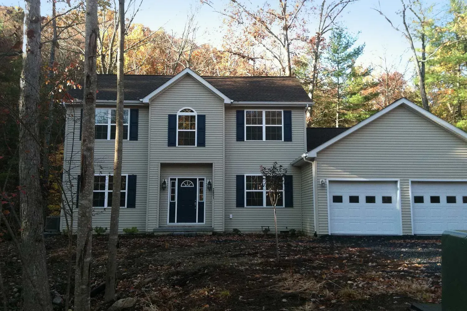 Two-story house with light siding, dark blue shutters, a two-car garage, and a dark blue front door.