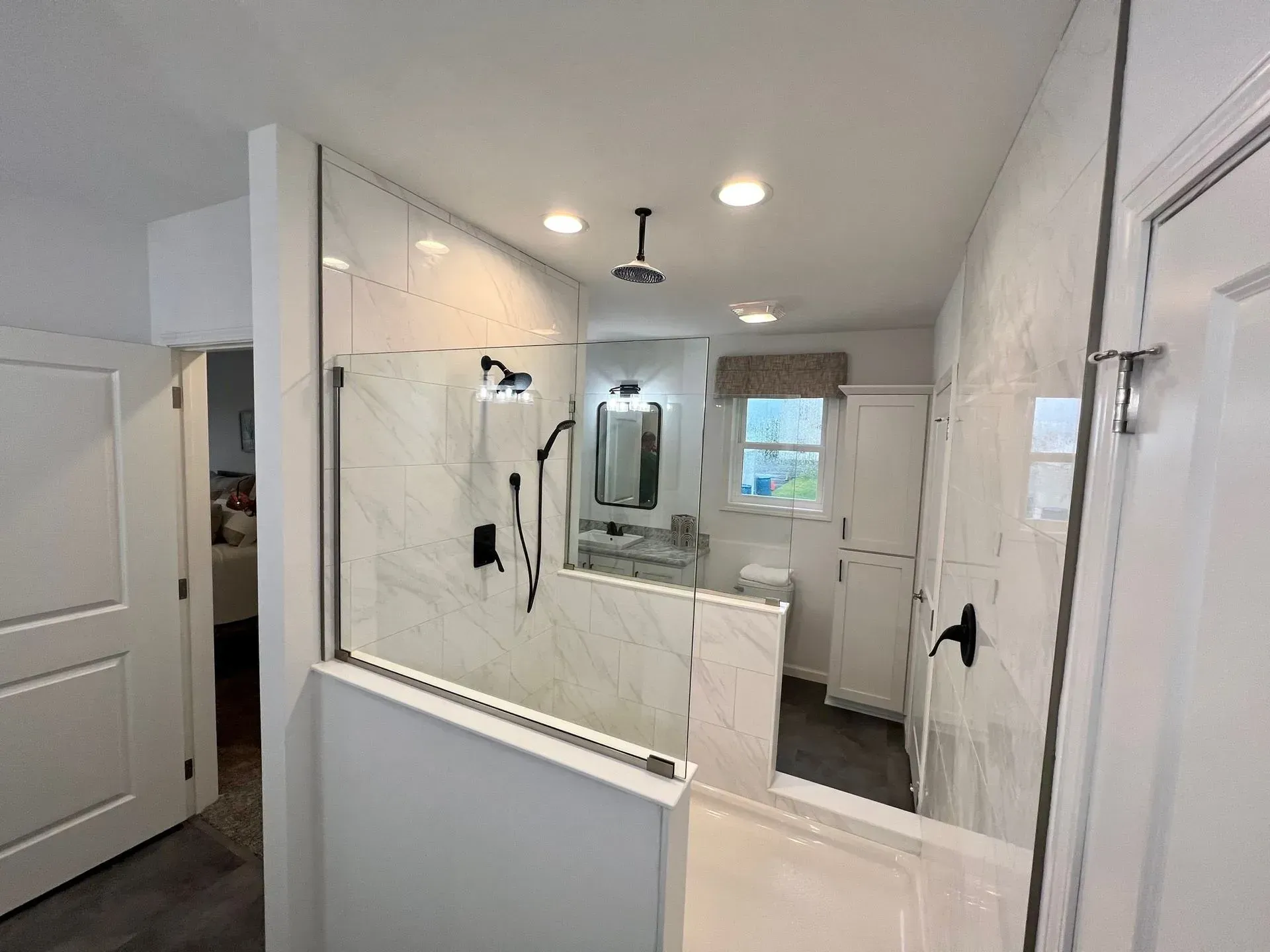 Modern bathroom with tiled walls, glass shower, and white fixtures.