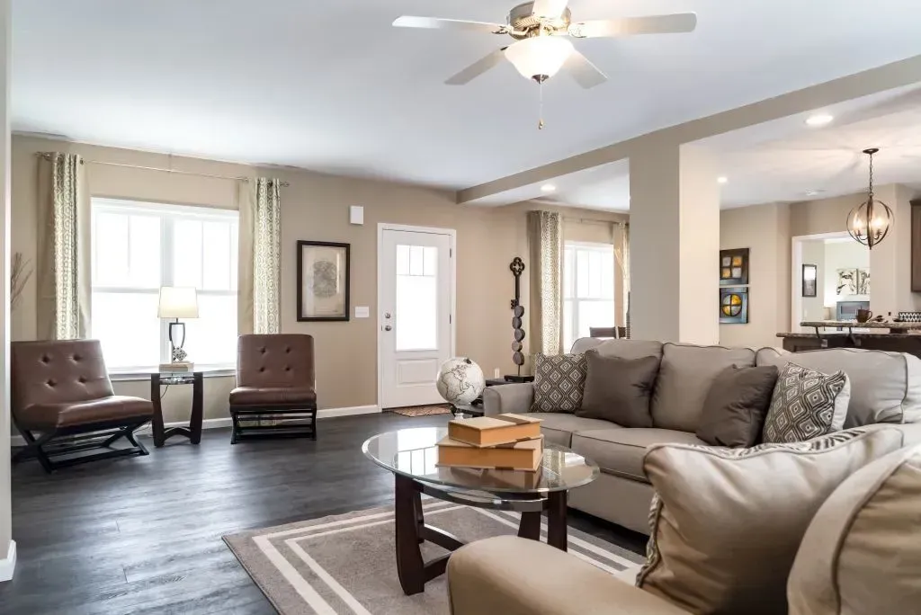 Spacious living room with tan walls, dark wood floor, and large couch near a glass coffee table.