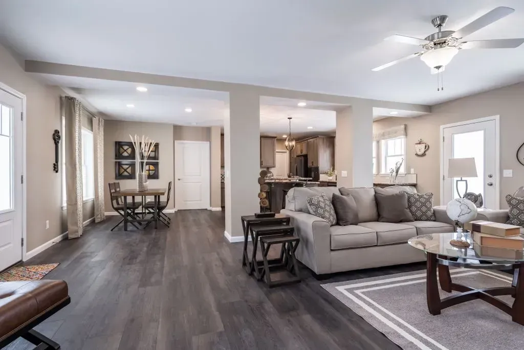 Open-concept living room with gray walls, dark wood floors, and a view into the dining area and kitchen.