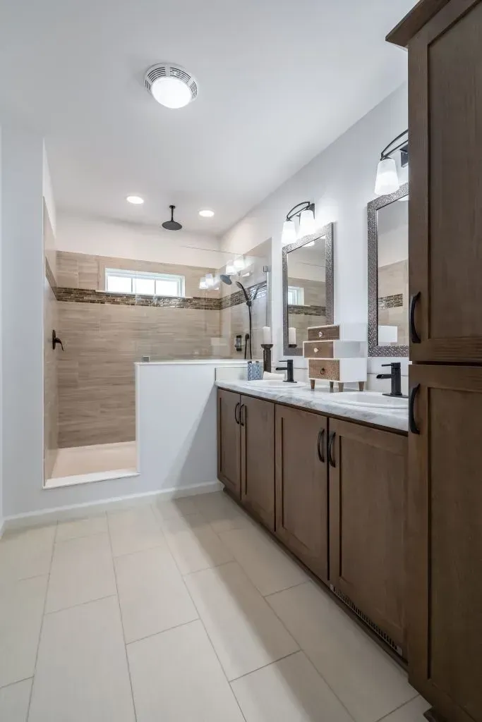 Bathroom with double vanity, shower, and light wood cabinetry; neutral tones.