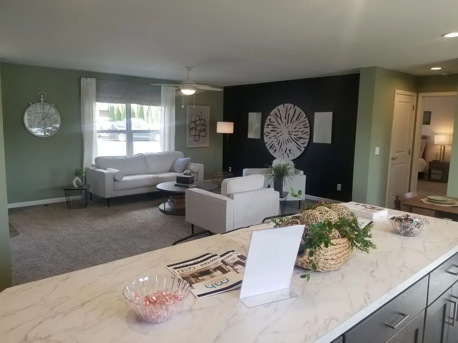 Living room with light-colored sofa, white chairs, coffee table, and dark accent wall.