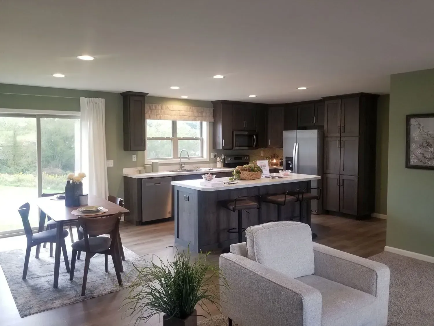Open-concept kitchen and living area with dark cabinets, white countertops, and a gray island.