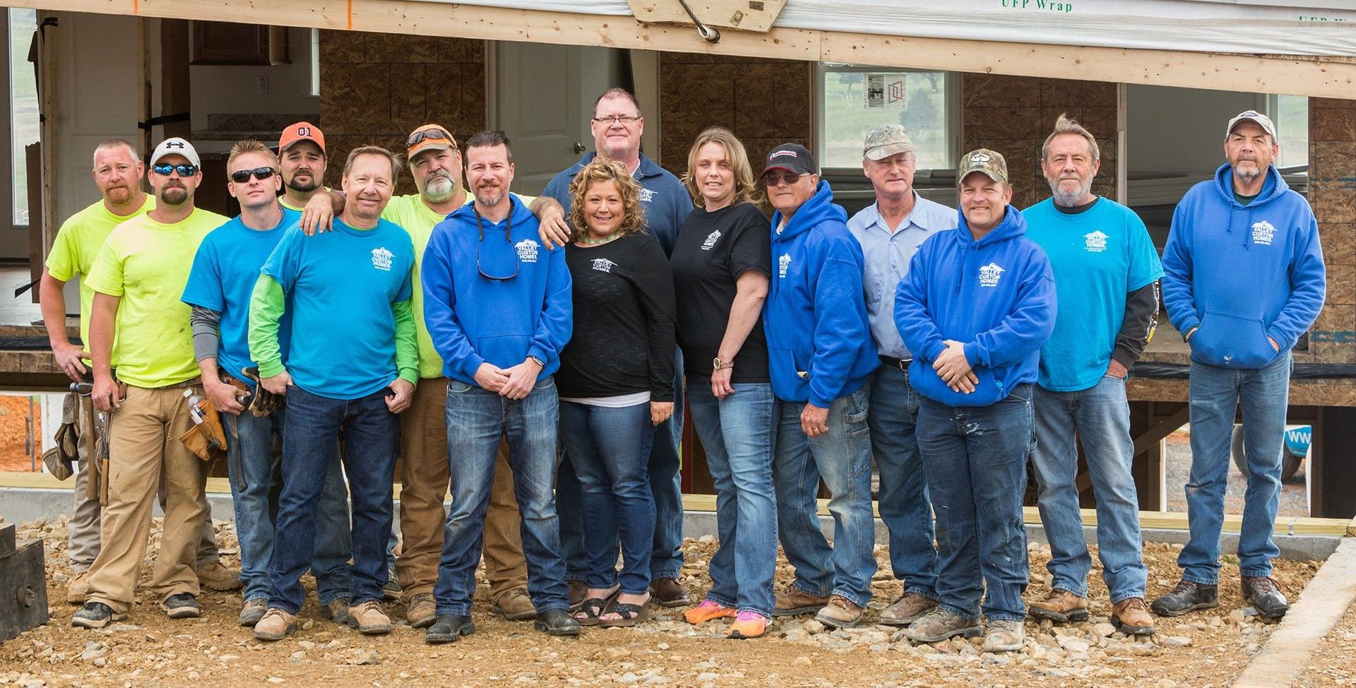 Group of people in blue and yellow shirts standing outside a building under construction.