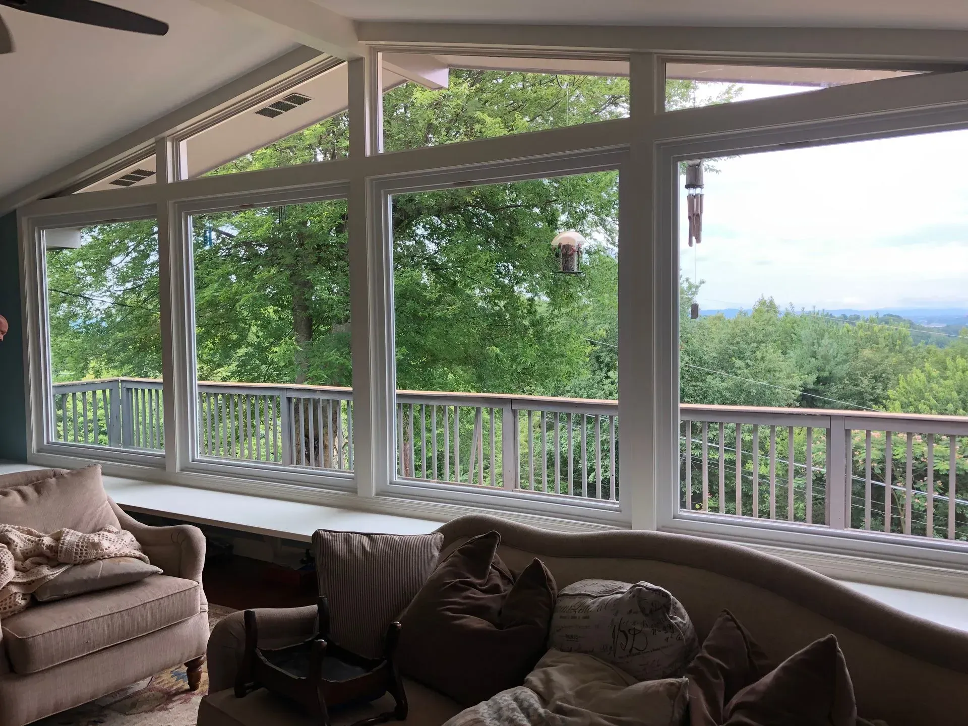 Bright living room with large windows overlooking a green hillside and distant mountains