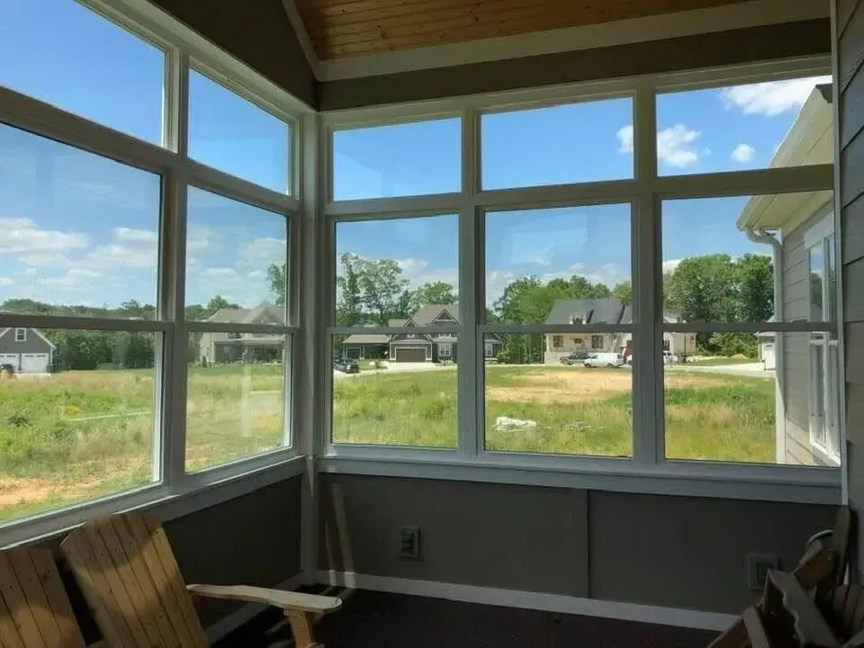 Sunroom with large windows overlooking a grassy neighborhood under a blue sky