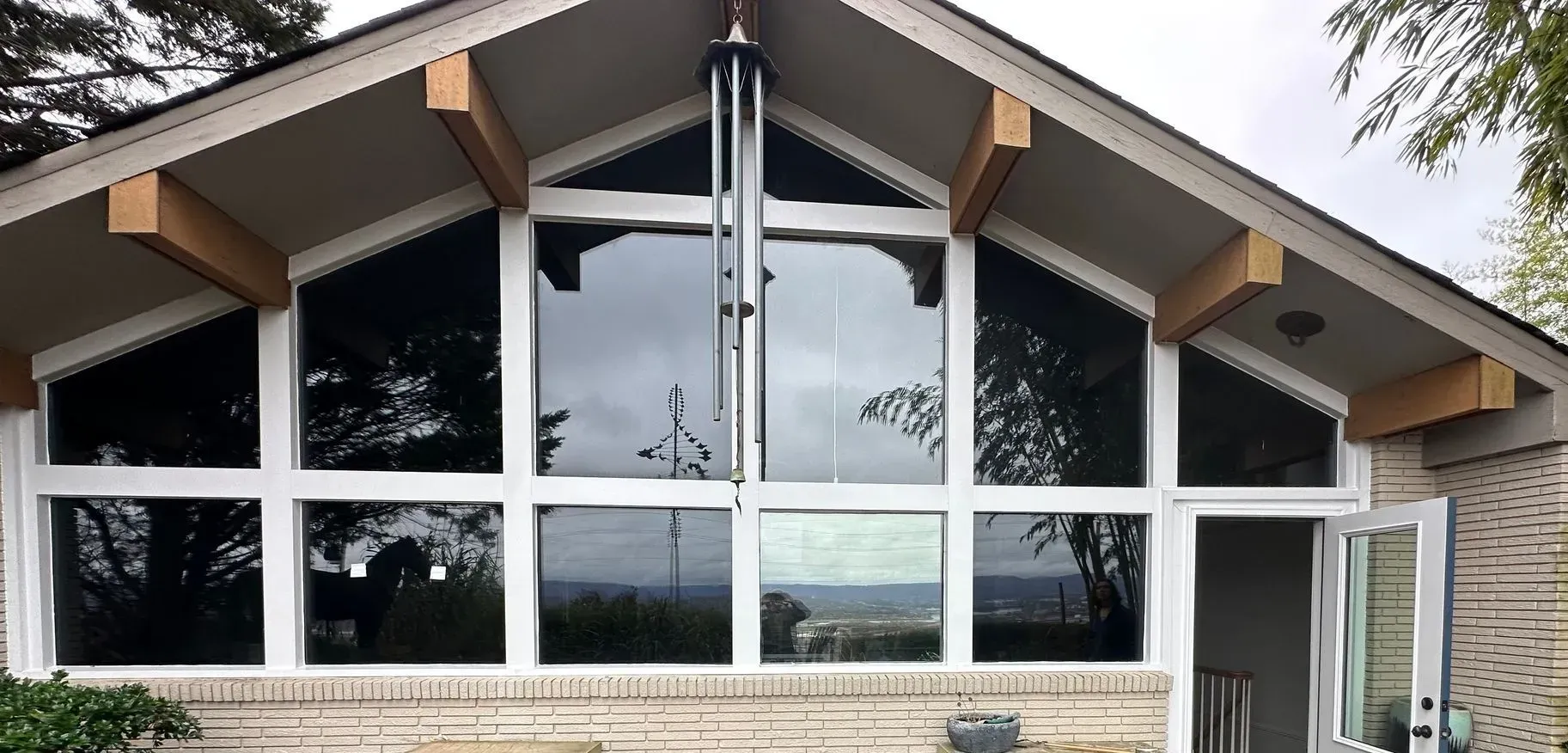 Modern A-frame building with large front windows, wood accents, and stone base, viewed from outside