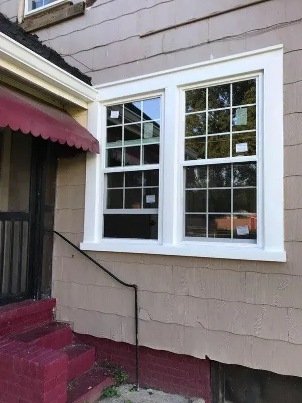 Exterior house window with white trim and two panes beside a red awning and steps
