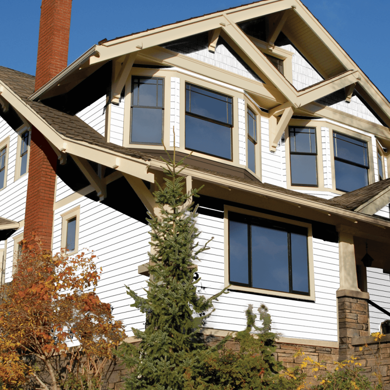 Two-story craftsman house with white siding, stone accents, and large dark-framed windows