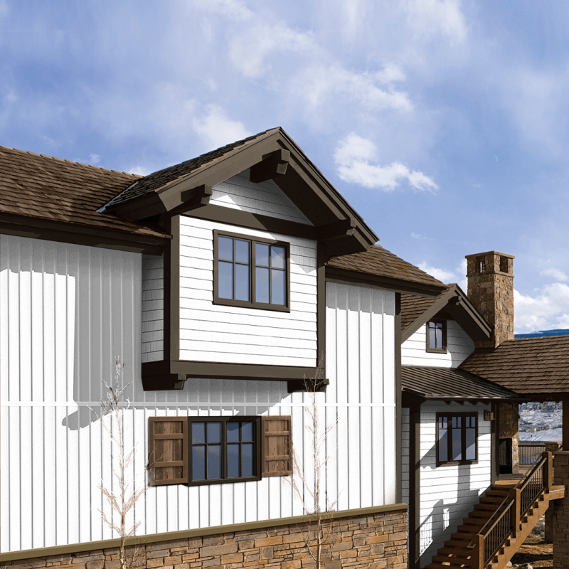 White chalet-style building with brown roofs, dark-trimmed windows, and a wooden walkway under a blue sky