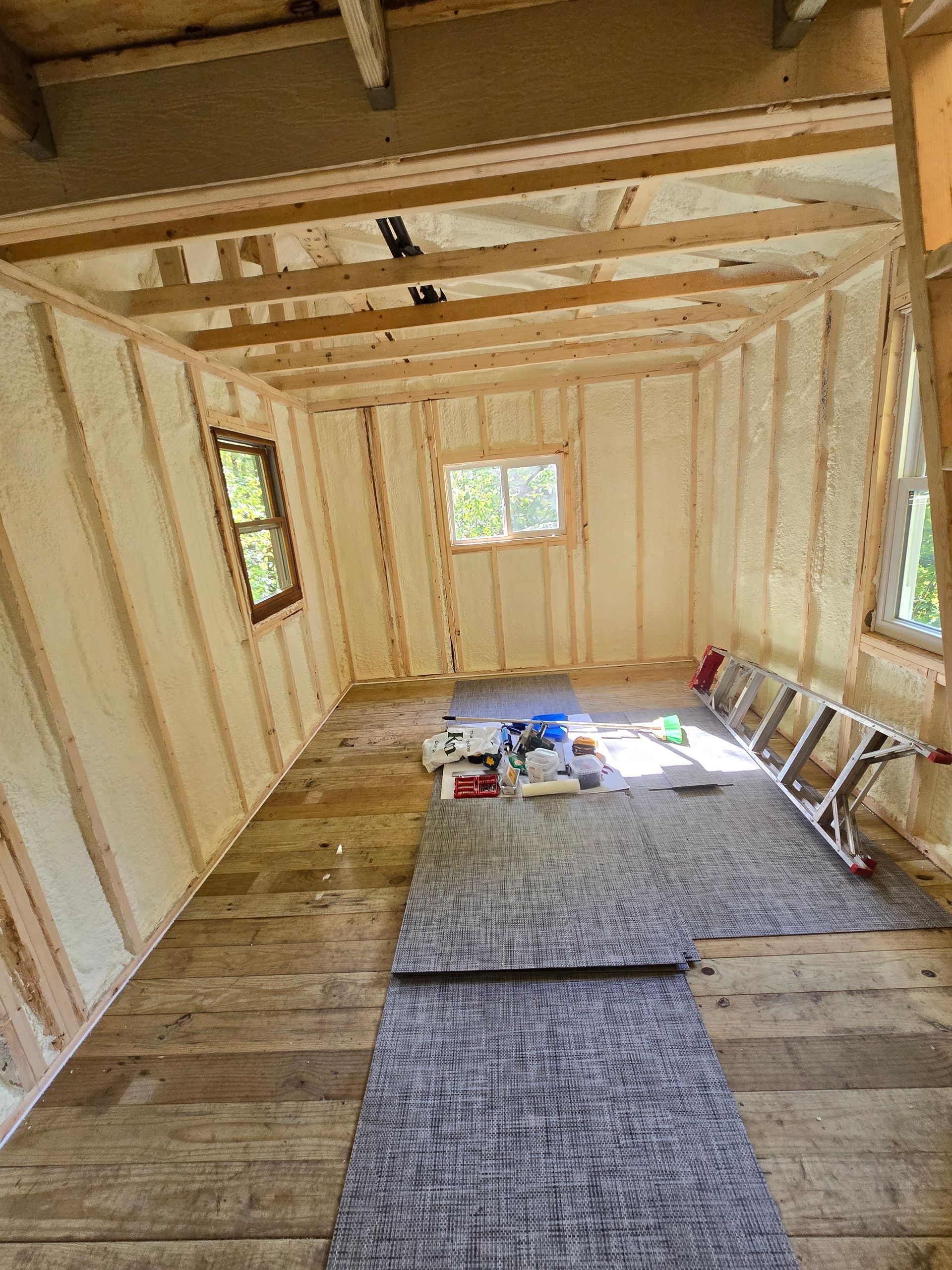 A room with a wooden floor and a ladder in it.