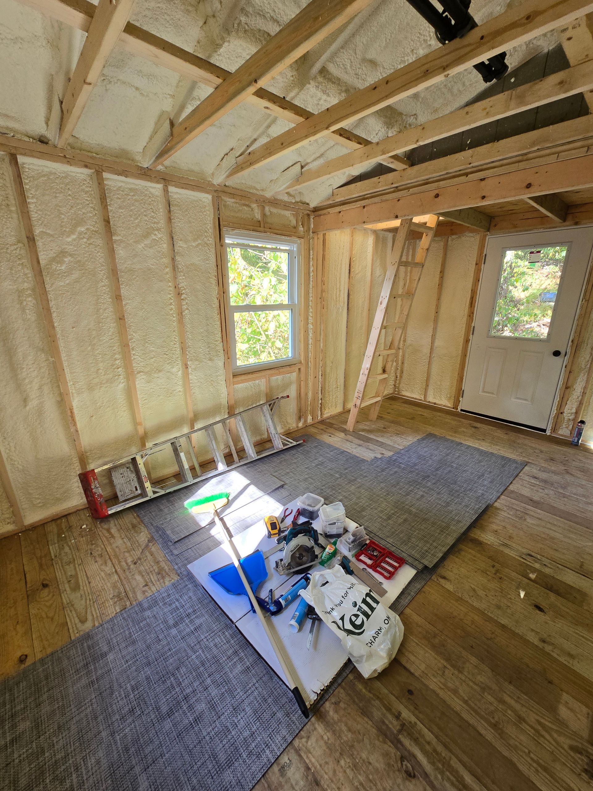 A room under construction with a ladder and tools on the floor.