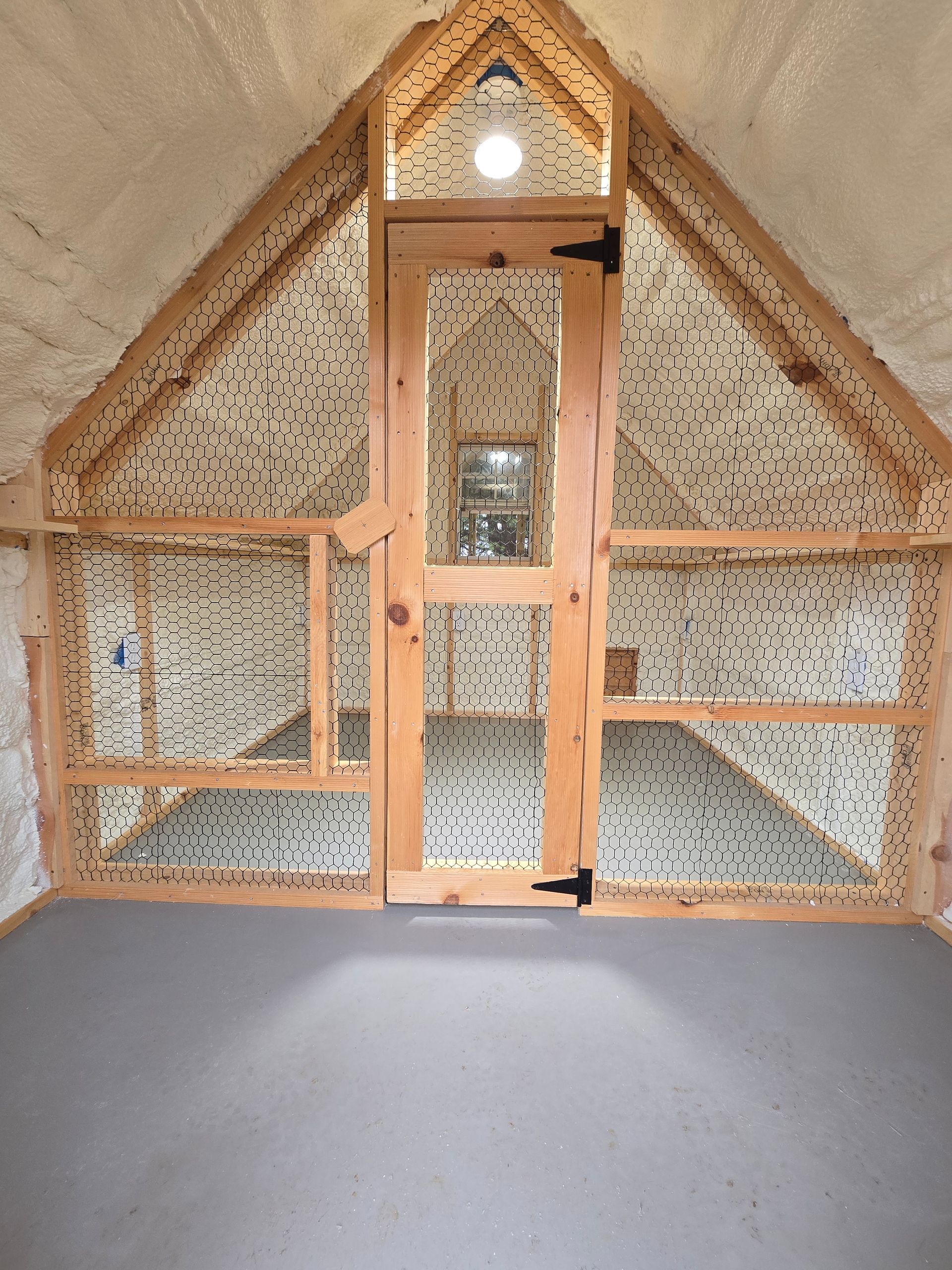 A room with a chicken coop in the attic and a door.