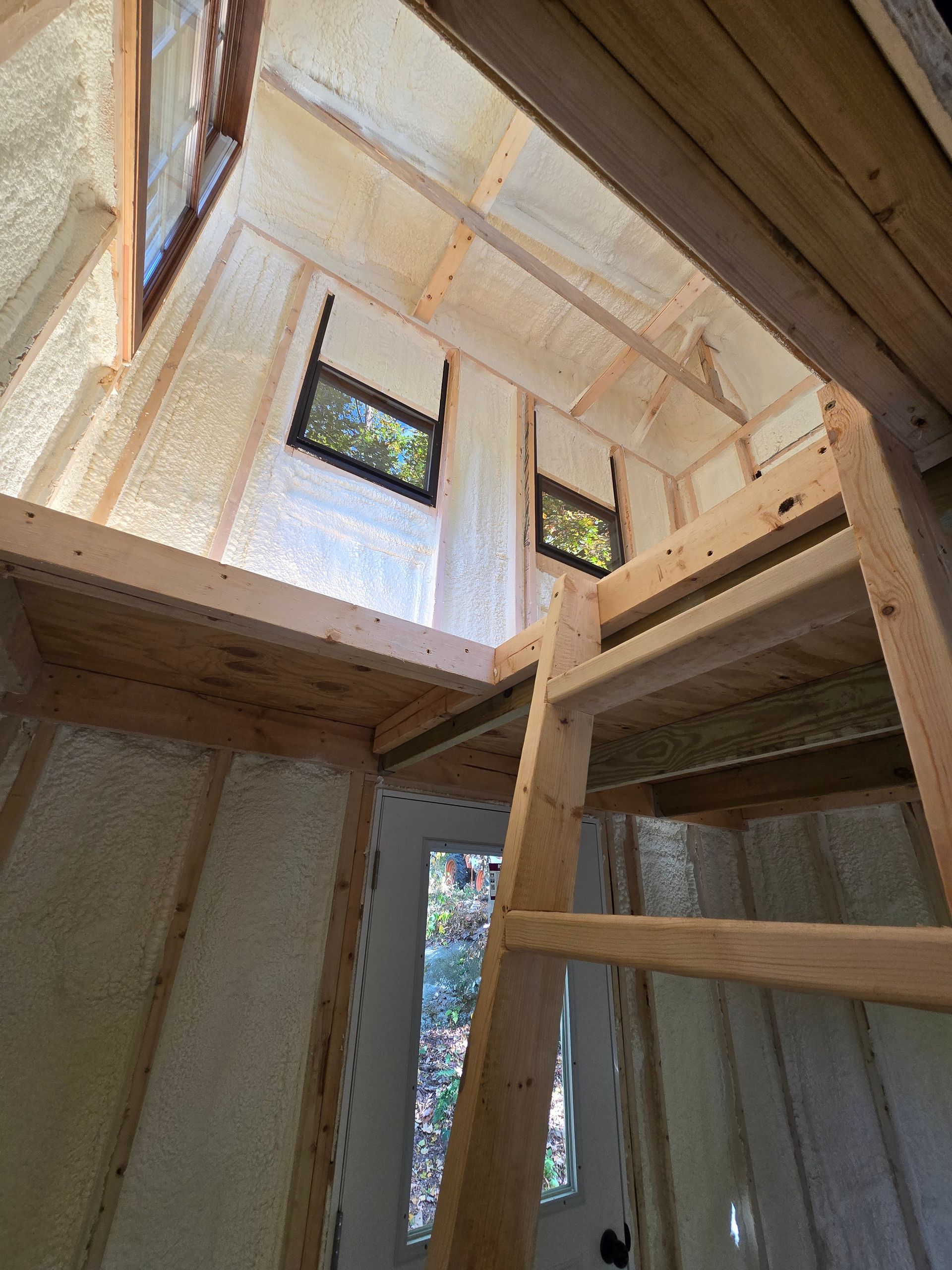 Looking up at the ceiling of a house with a ladder and windows.