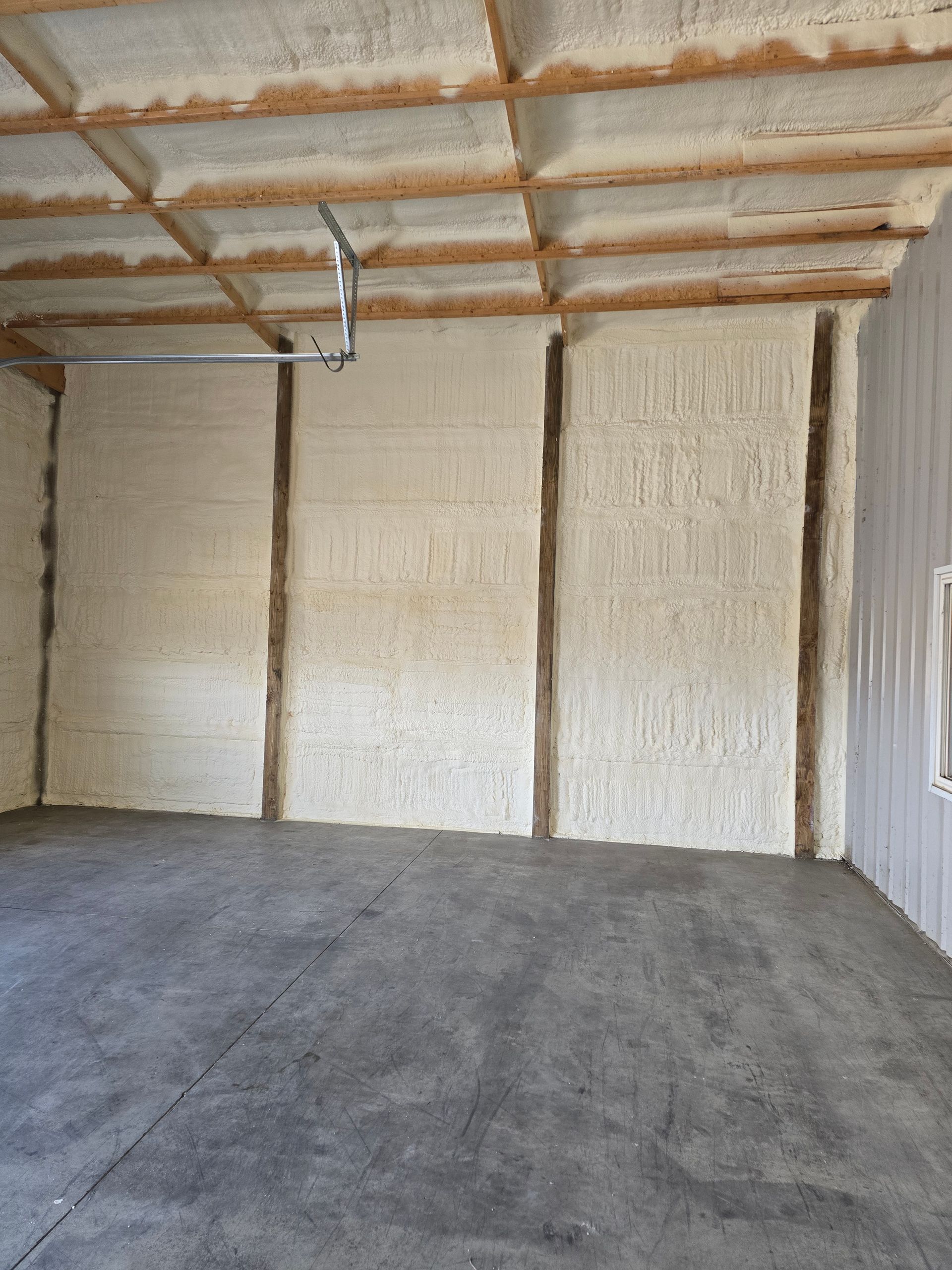 An empty garage with a garage door open and a lot of insulation on the walls and ceiling.