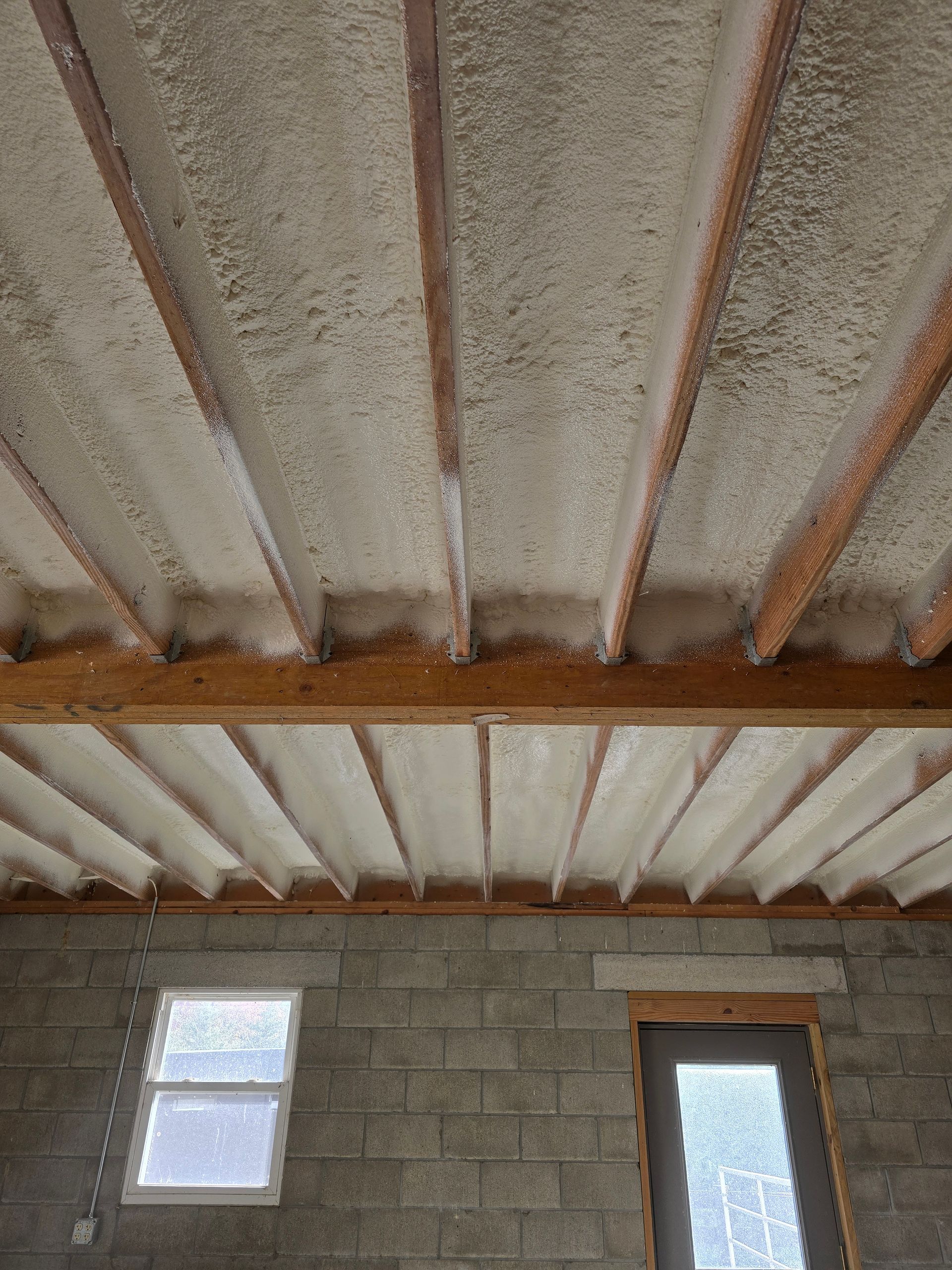 A room with a ceiling that is covered in foam and a window.