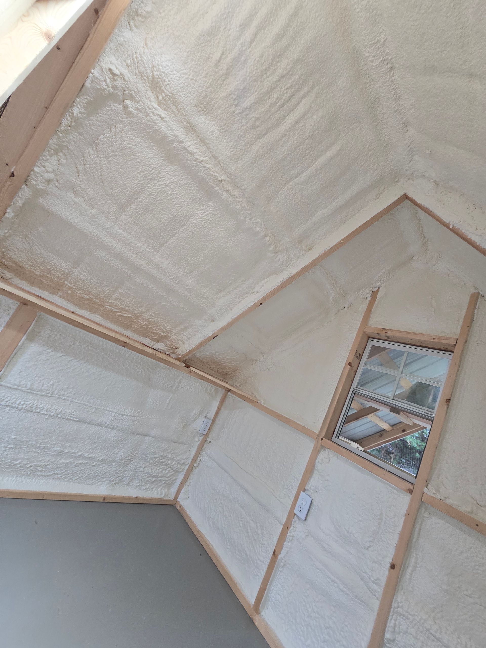 A room with a ceiling that is covered in foam and a window.