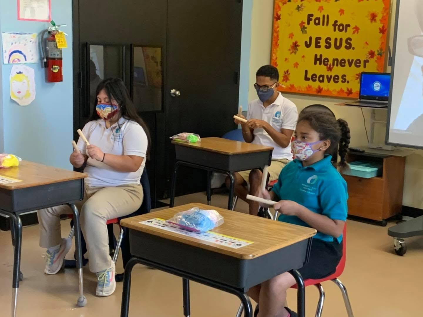 Students wearing masks seated at desks in a classroom, working quietly during class.