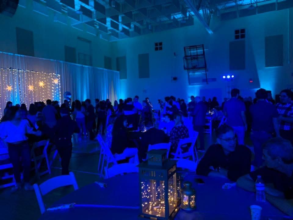 Blue-lit banquet hall with seated guests and glowing lantern centerpieces