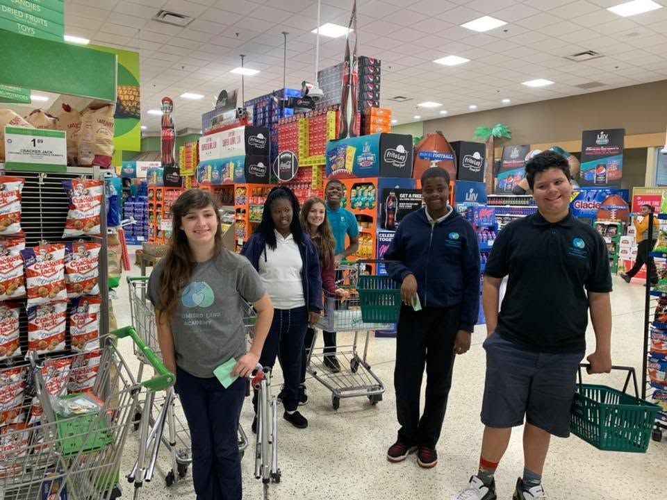 Four people posing with shopping carts in a brightly lit grocery store aisle