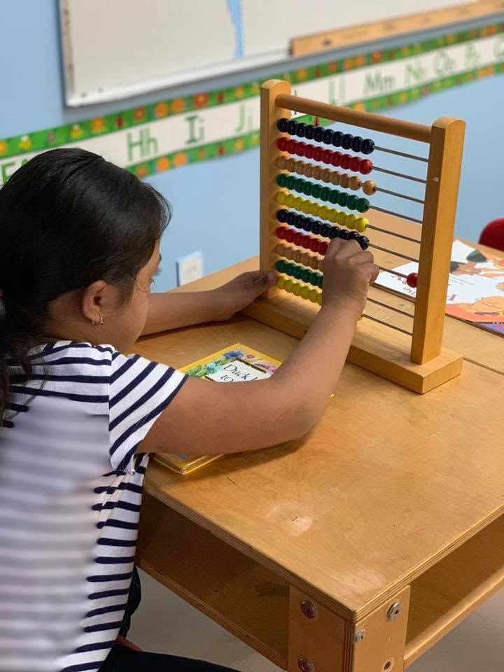 Child using a colorful abacus at a classroom table