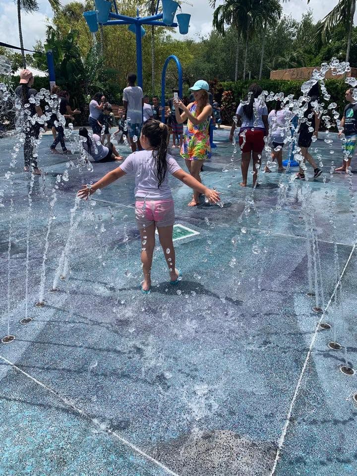 Children playing in a splash pad with water jets on a sunny day