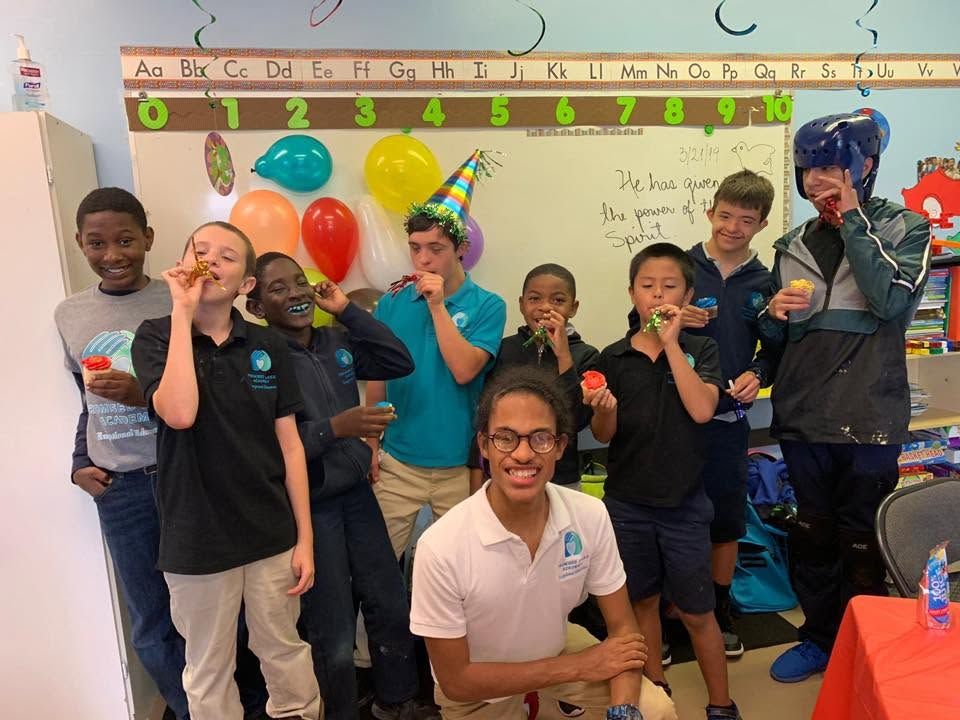 Classroom celebration with children holding colorful balloons and making playful faces