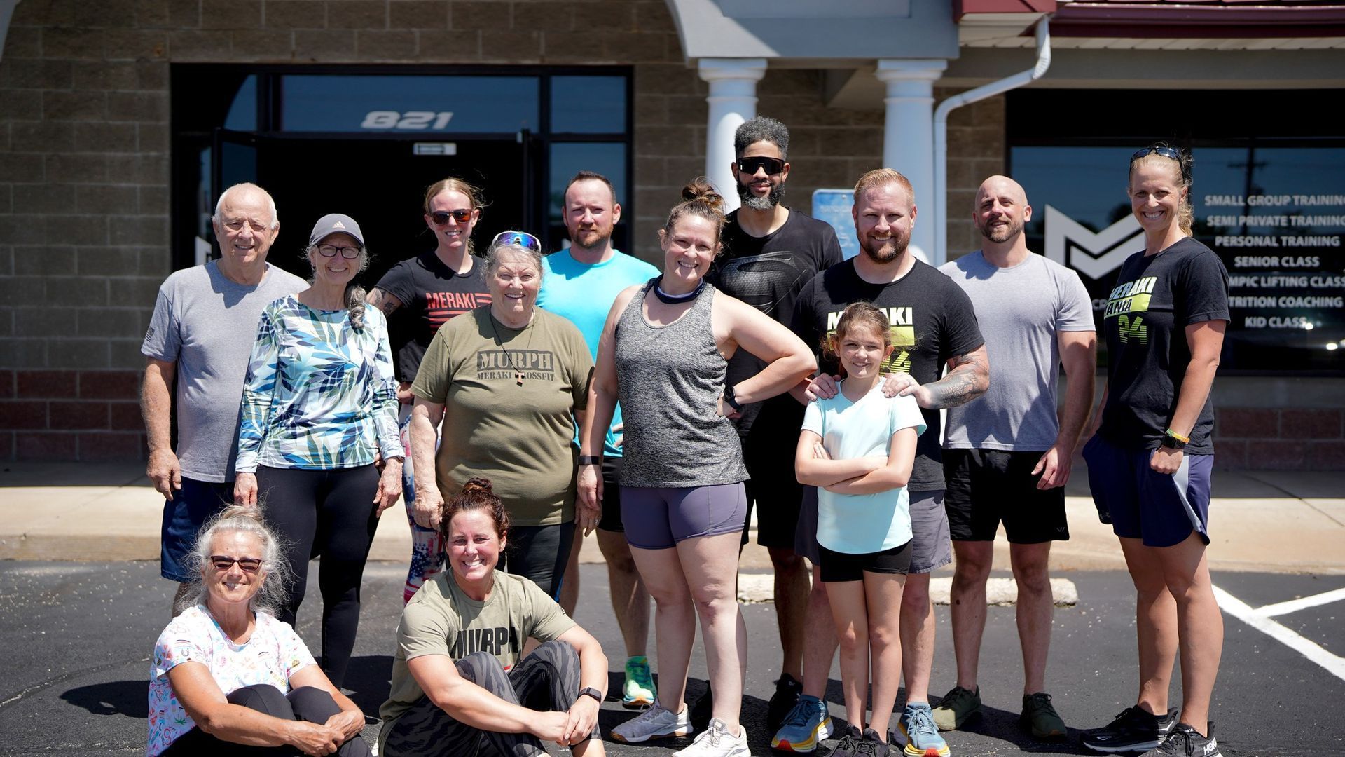 Group of people posing outside a building with a black door. The group smiles and poses for the camera.
