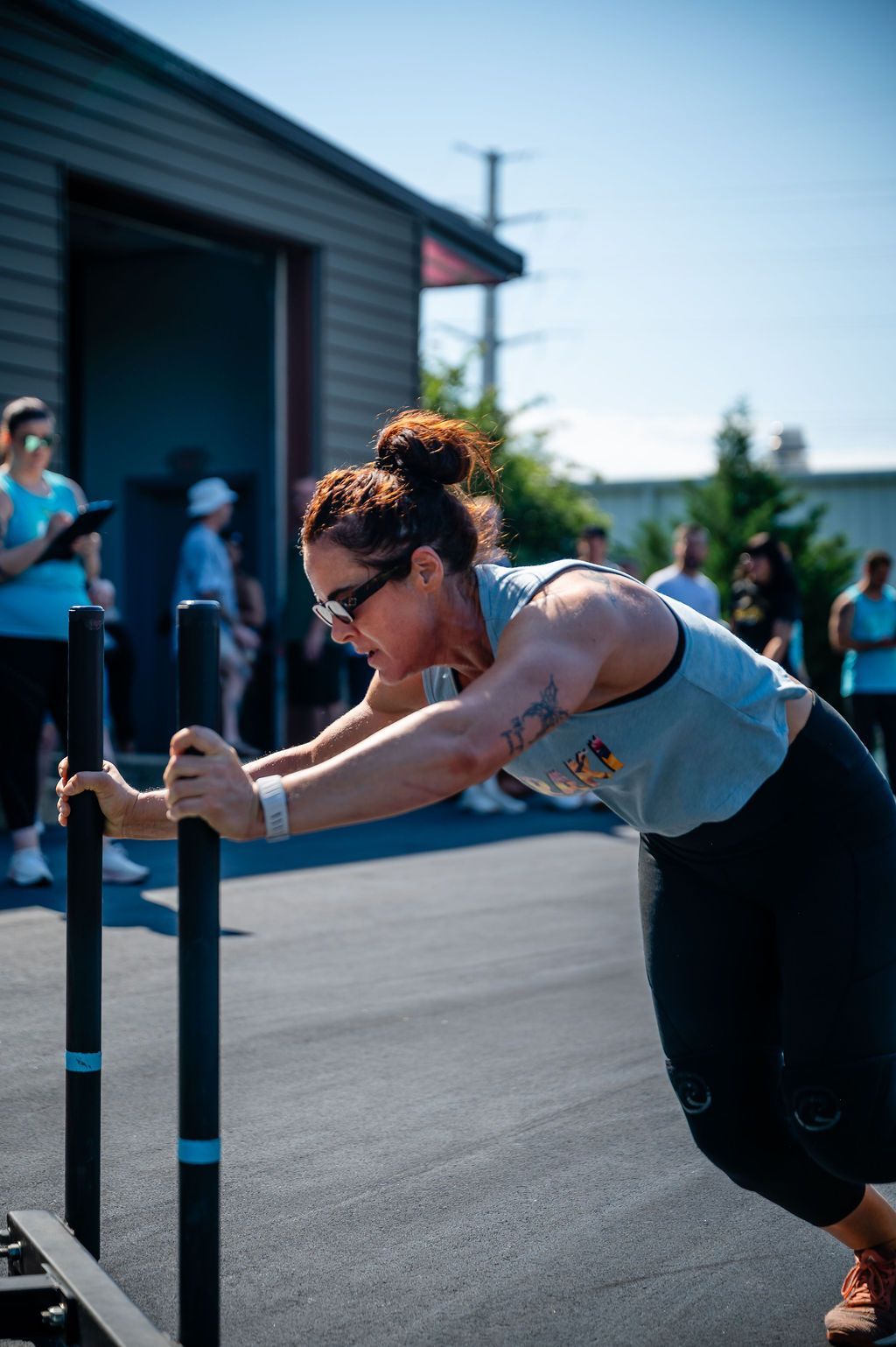 Person pushing a sled on pavement during an outdoor workout near a building