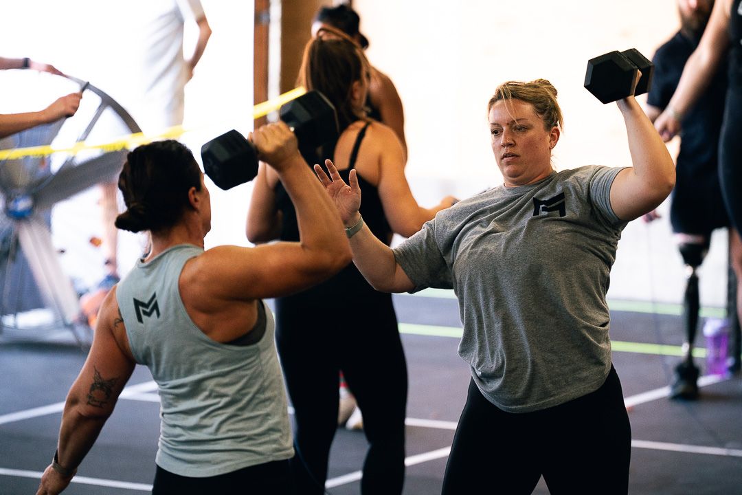 People exercising in a group fitness class, lifting dumbbells in a gym