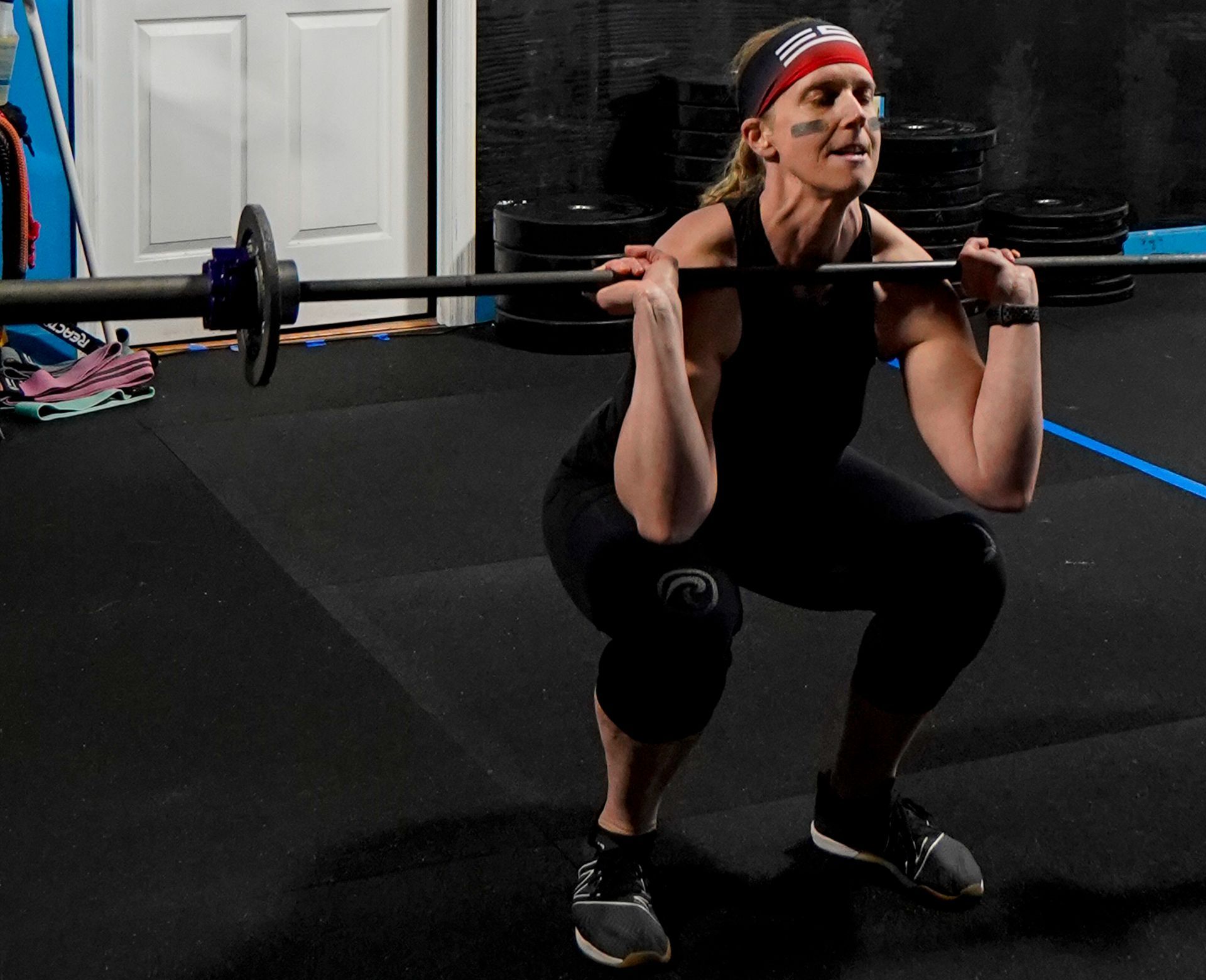 Woman performing a front squat with a barbell in a gym.