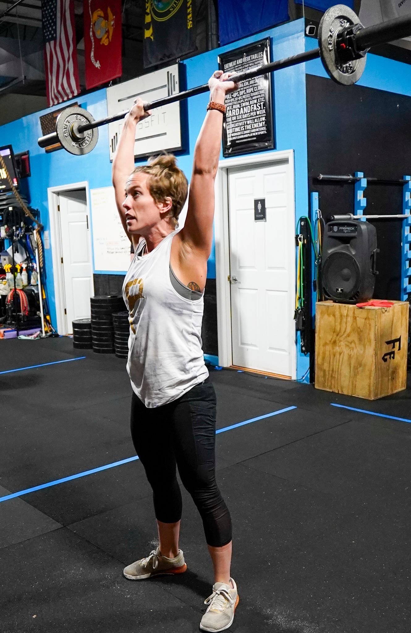 Woman lifting a barbell overhead in a CrossFit gym
