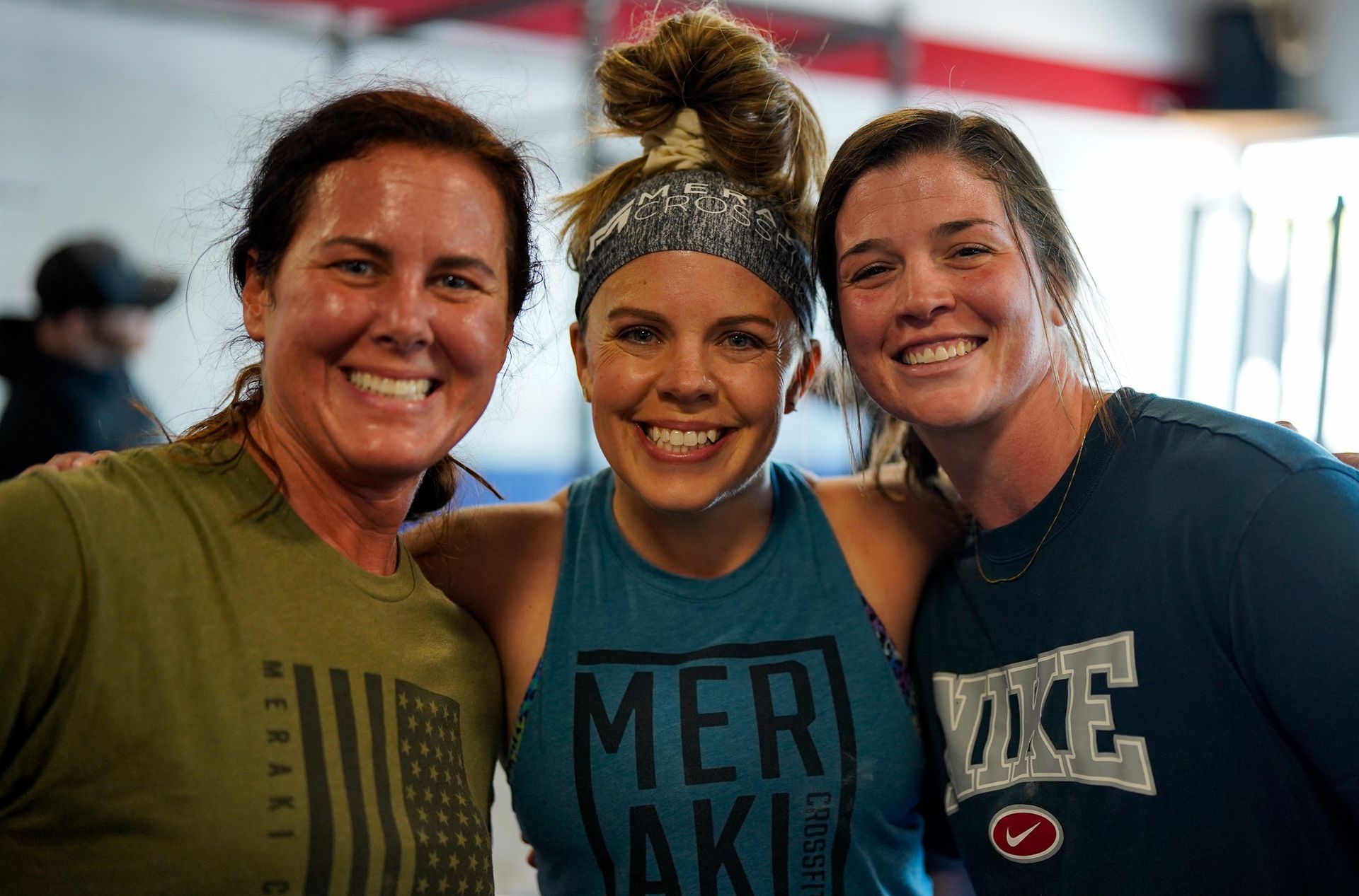 Three smiling athletes posing indoors in workout shirts and headbands
