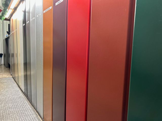 Row of colorful metal panels in a narrow indoor hallway, including silver, gray, brown, red, and green.