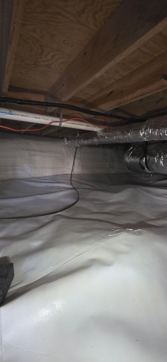View of a crawl space with white vapor barrier, exposed beams and ductwork. Electrical wire runs through the space.