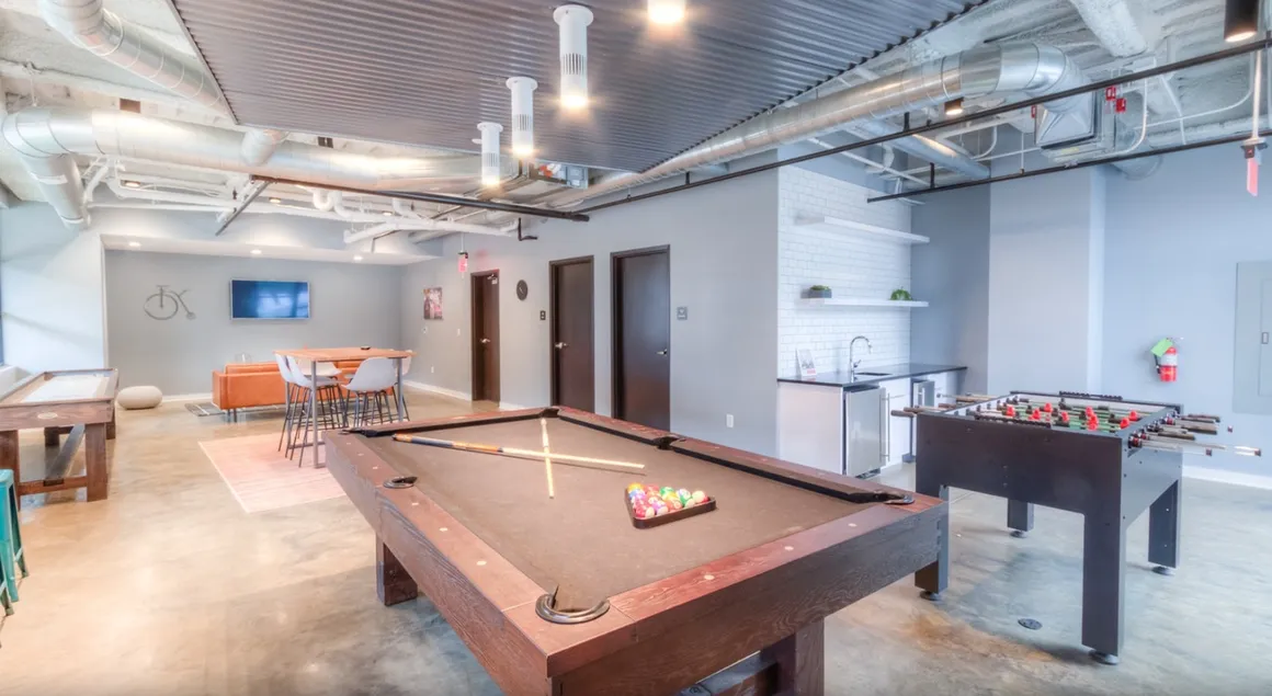 Game room with pool table, foosball, lounge area, and a small kitchenette.