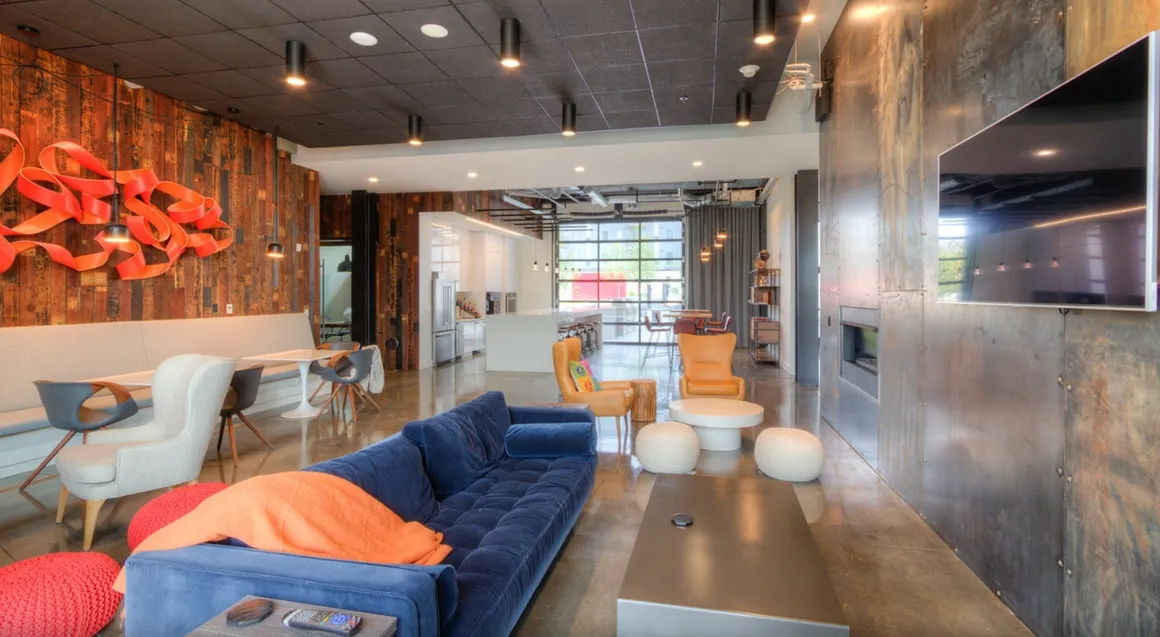 Modern living room with blue sofa, wooden wall, TV, and open doorway.