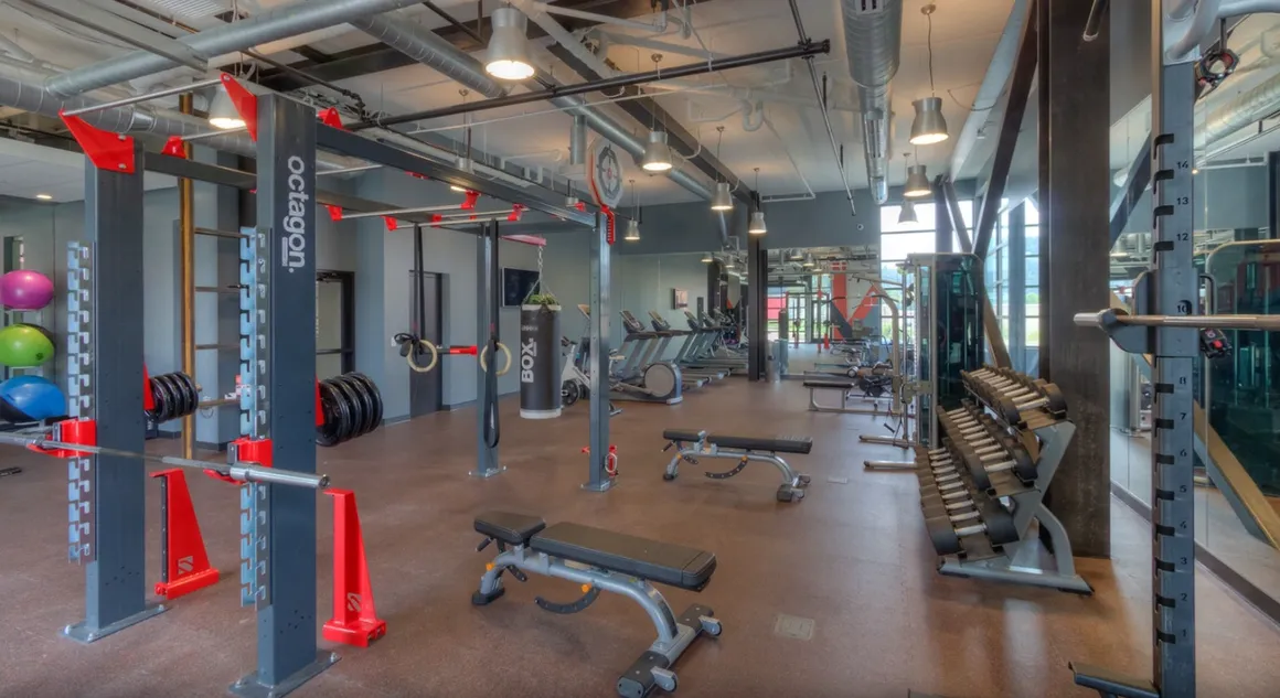 Gym interior with weight racks, benches, and exercise equipment.