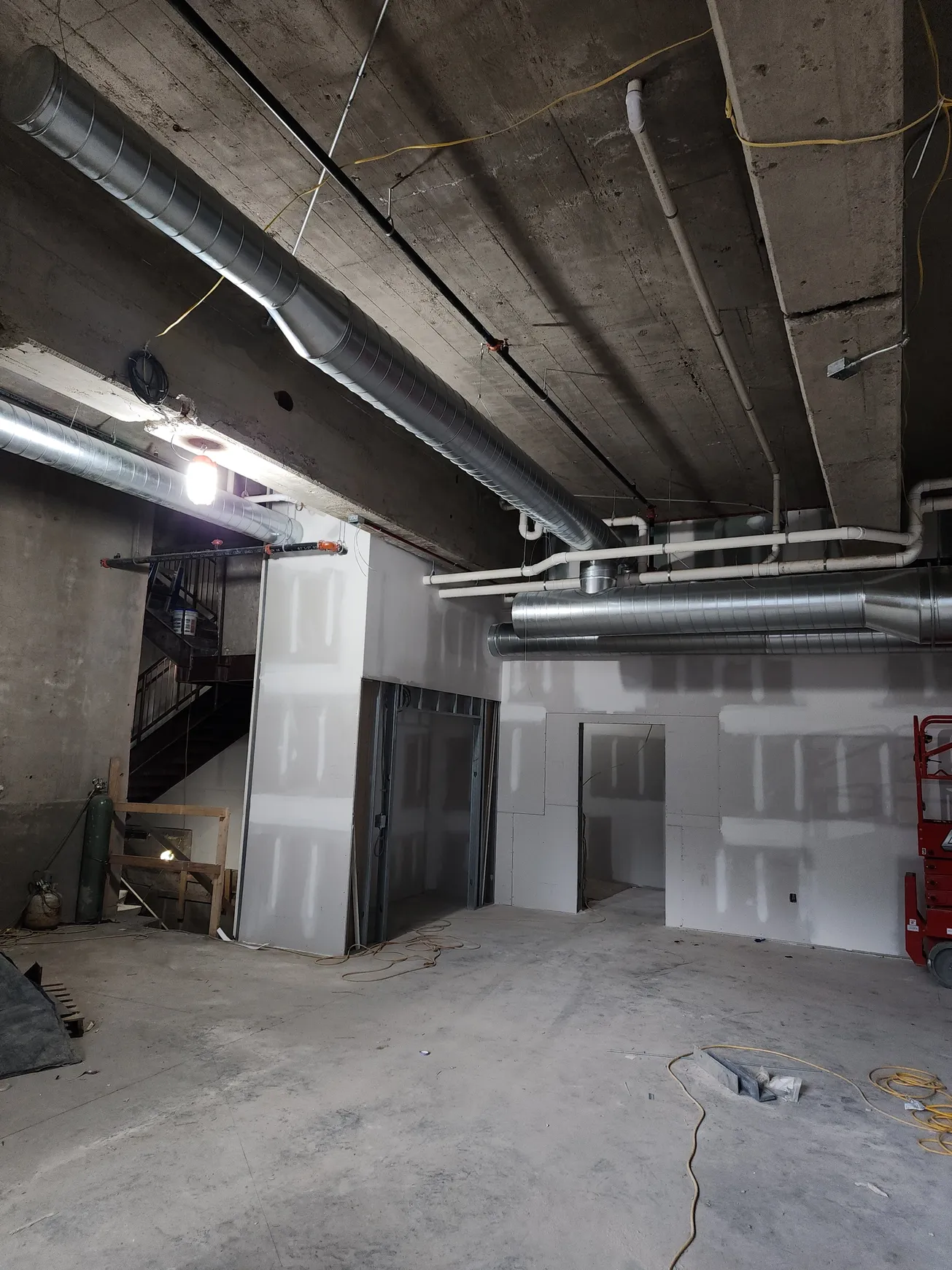 Construction site with unfinished walls and exposed ductwork, concrete ceiling.