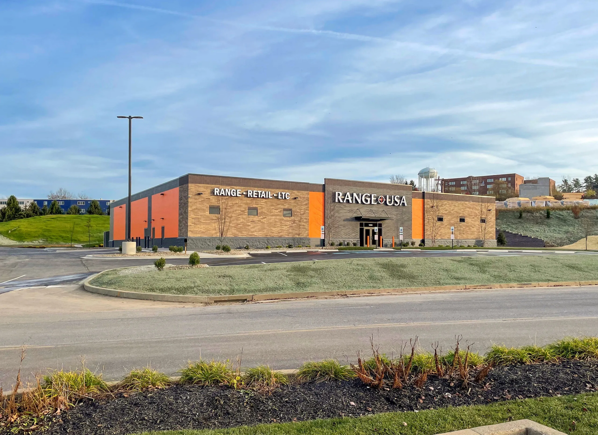 A large brick building with orange accents and a sign for Dave & Buster's. Overcast sky.