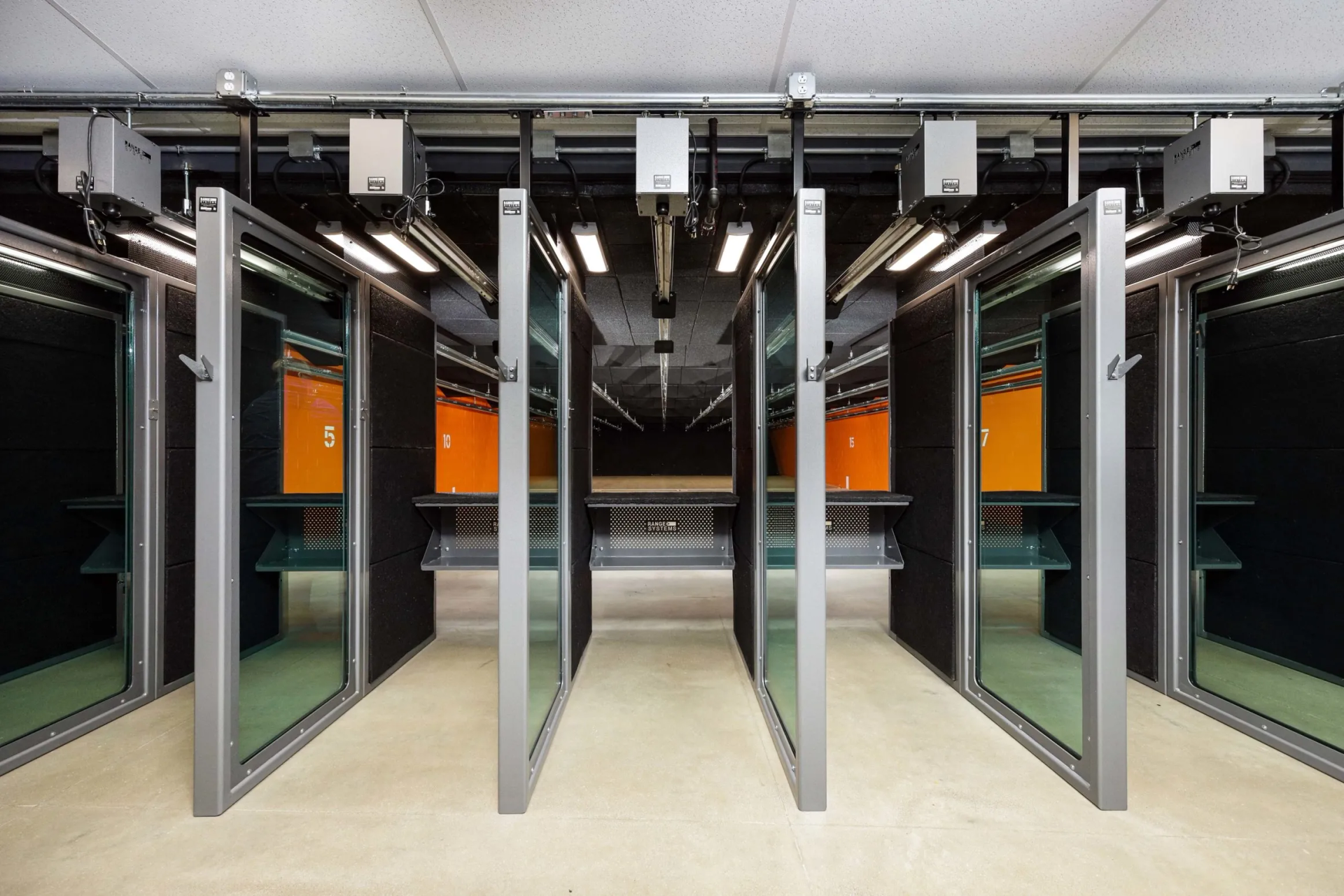 Shooting range with several enclosed lanes, each with a glass barrier and target backdrops.