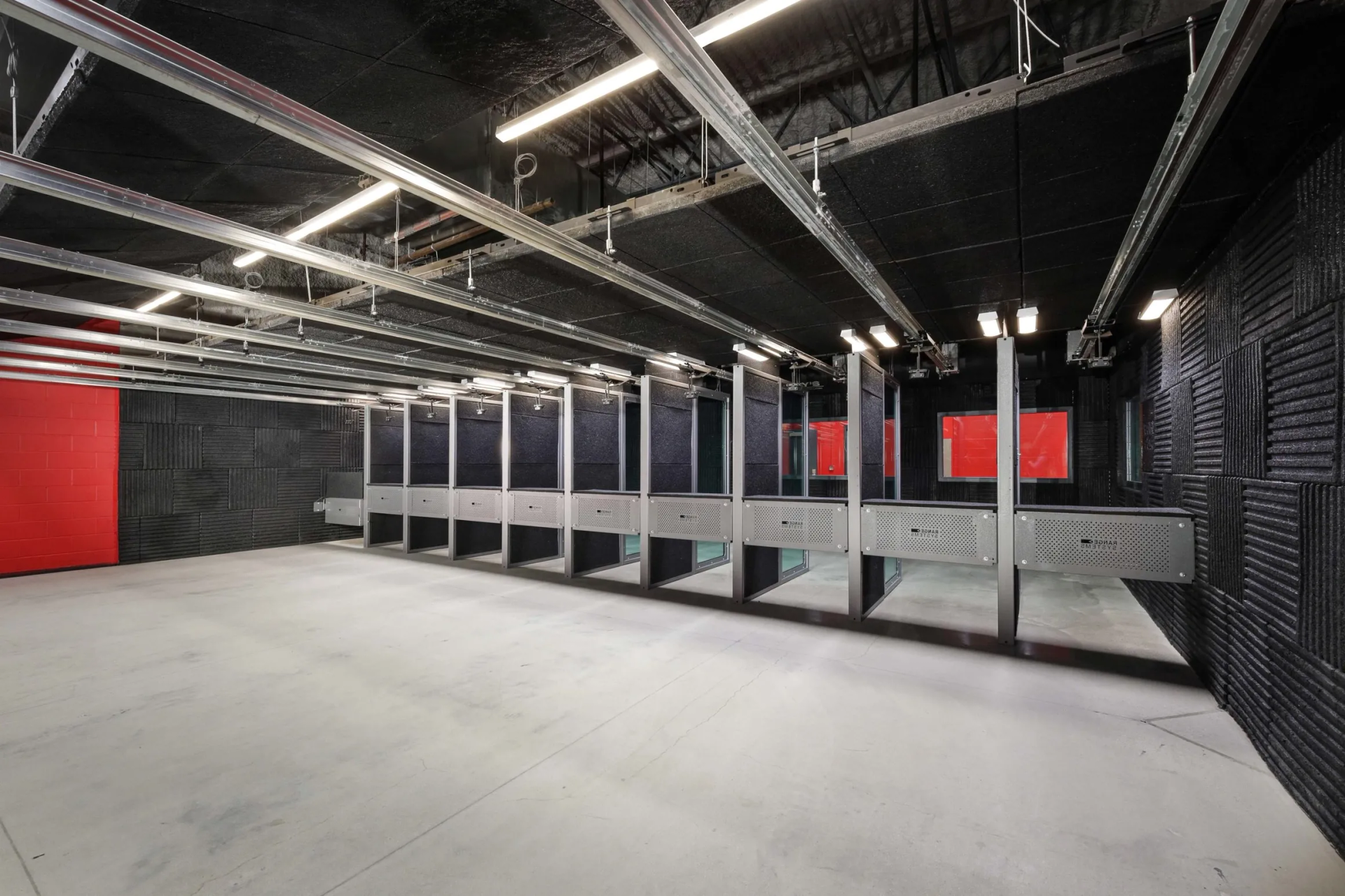 Empty indoor shooting range with stalls, red target areas, and soundproofing on walls.