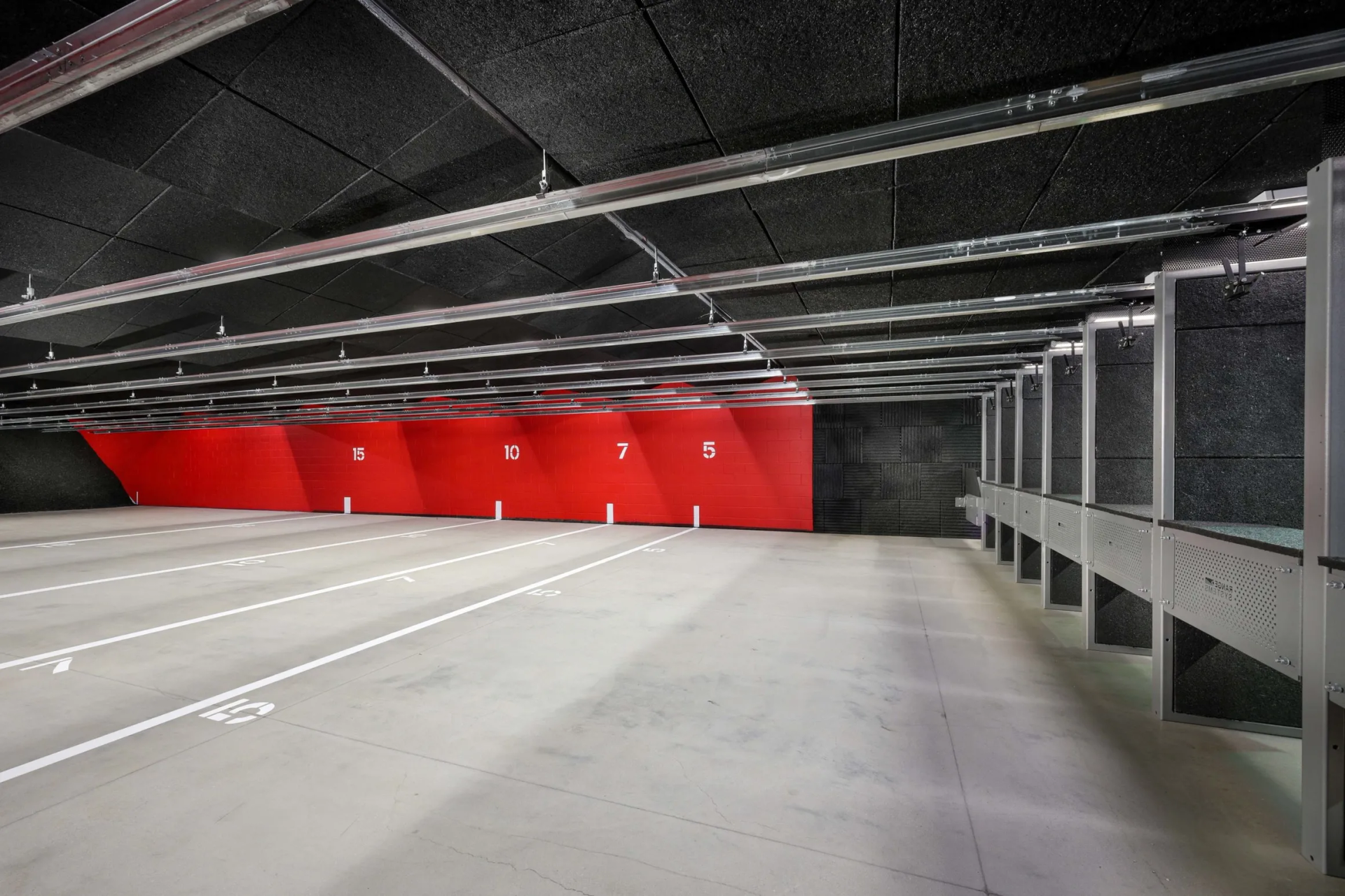 Indoor shooting range with stalls, targets, and red back wall.